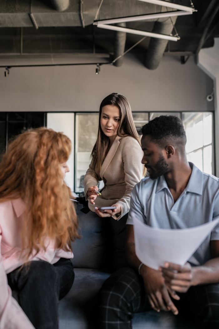 A diverse team engaging in a collaborative office meeting with documents and smartphones.