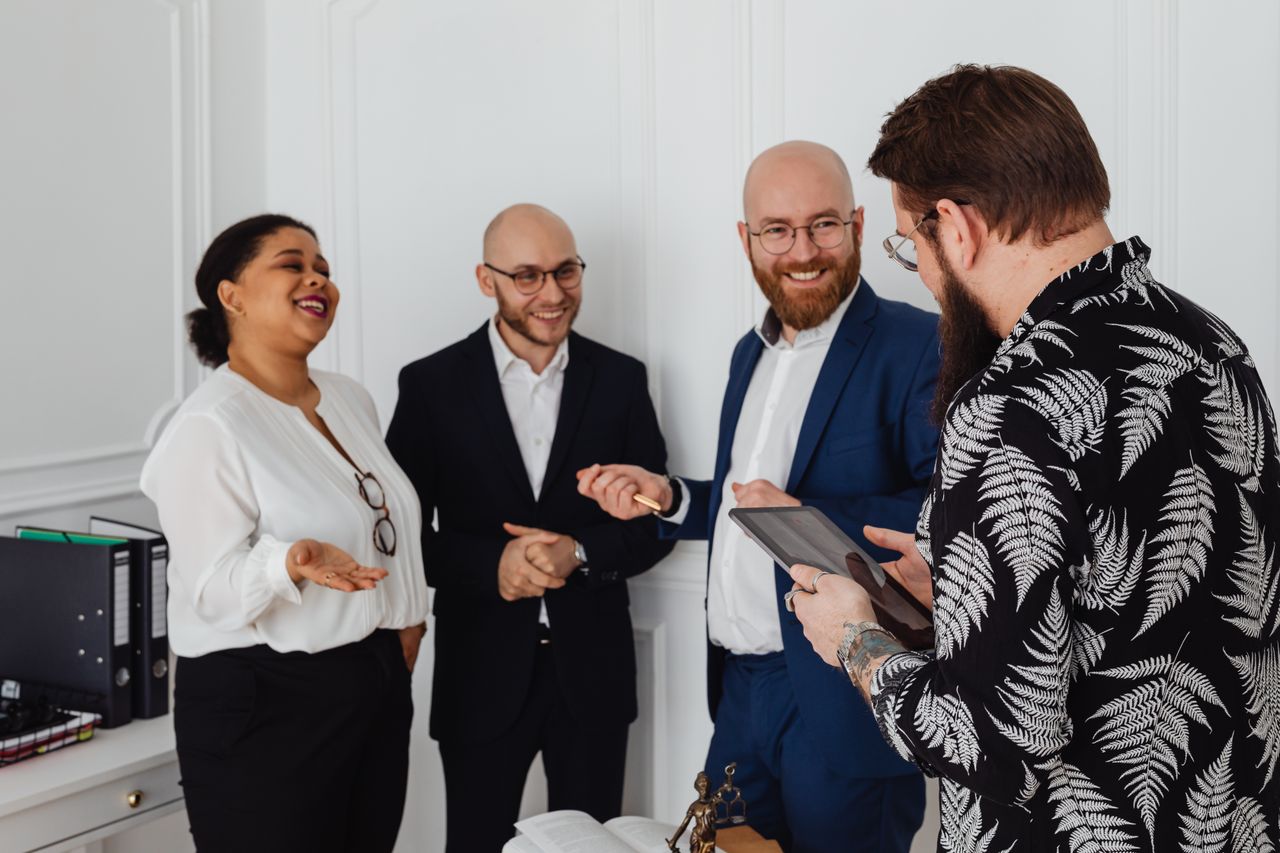 A diverse group of business professionals smiling and discussing ideas in an office setting.