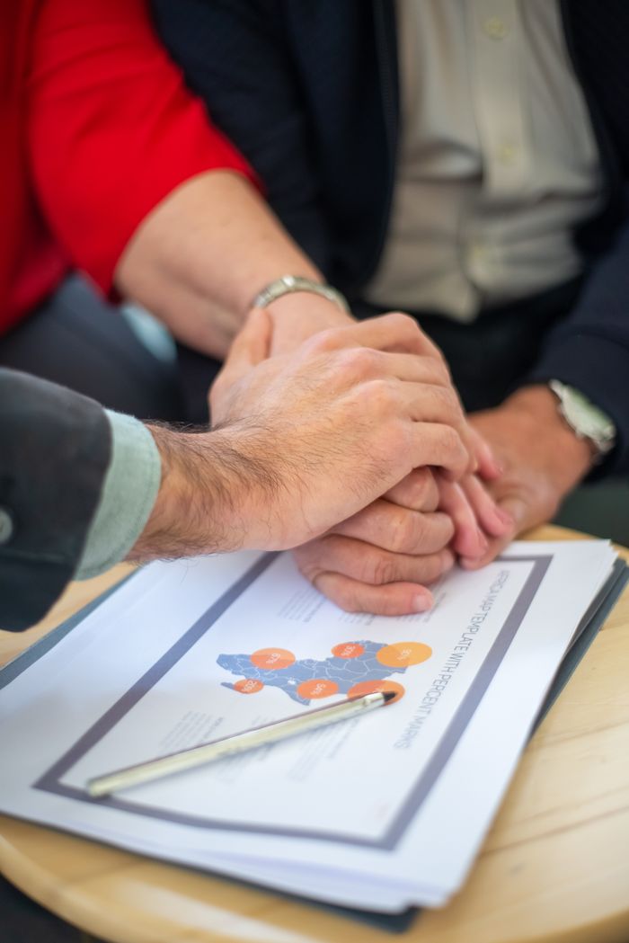 hero-homepage Close-up of hands together over business documents symbolizing teamwork and collaboration.